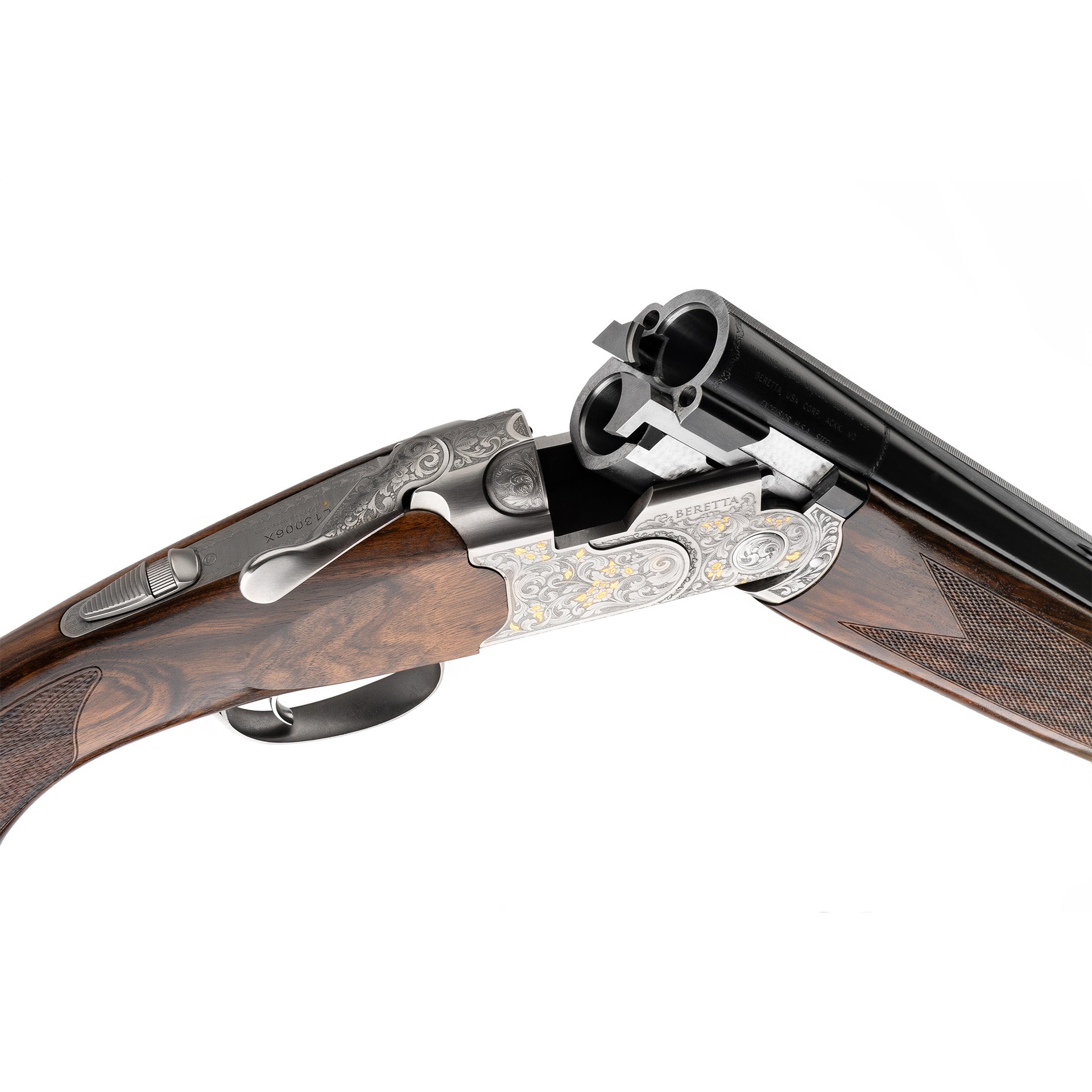 Close-up of a double-barrel shotgun with a dark brown wood stock, polished black metal barrels, and ornate silver-toned metal receiver and lockplate with gold detailing, shown on a white background.