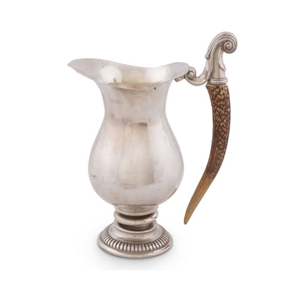 Silver pitcher with a decorative horn handle on a white background